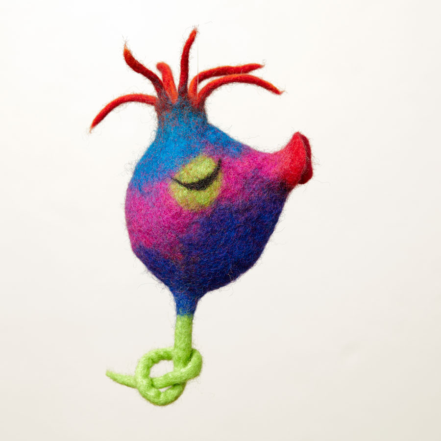 Das Bild zeigt eine Figur aus bunter Wolle, die - mit etwas Fantasie - einer Beere ähnelt. Sie hat eine Art Fruchtstempel und einen Stängel.